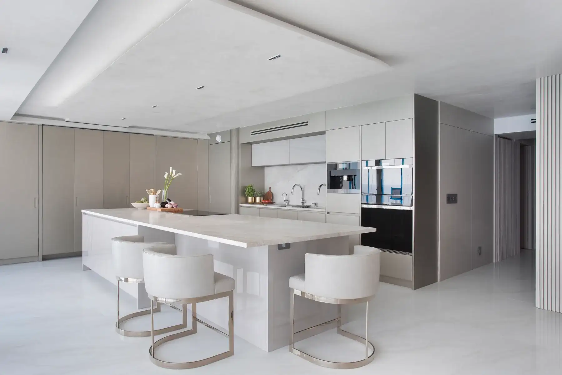 White lacquer kitchen with waterfall island, bar seating and polished marble floors in the Boca Raton high-rise residence