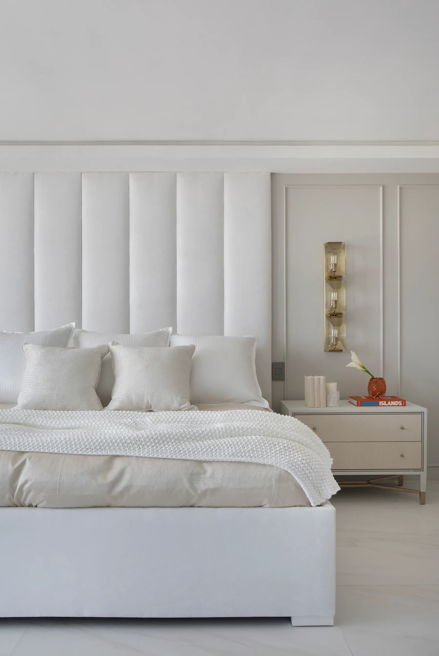 Primary bedroom with a channel-tufted headboard, wall sconces and layered neutral bedding