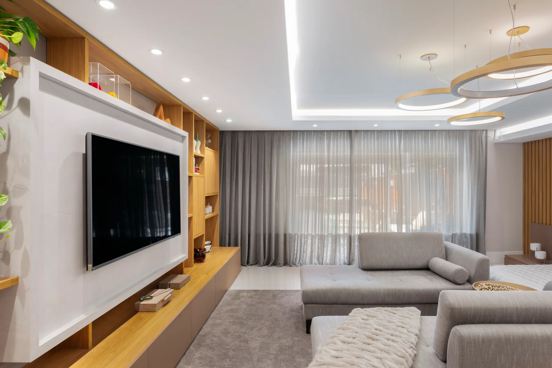 HOME IT media wall with long oak cabinetry, concealed television storage and integrated lighting