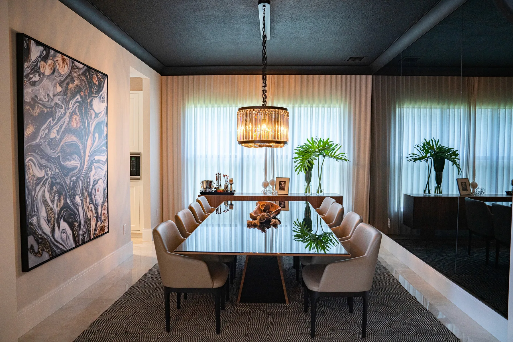 Dining room with a sculptural chandelier, upholstered chairs and a dark tray ceiling