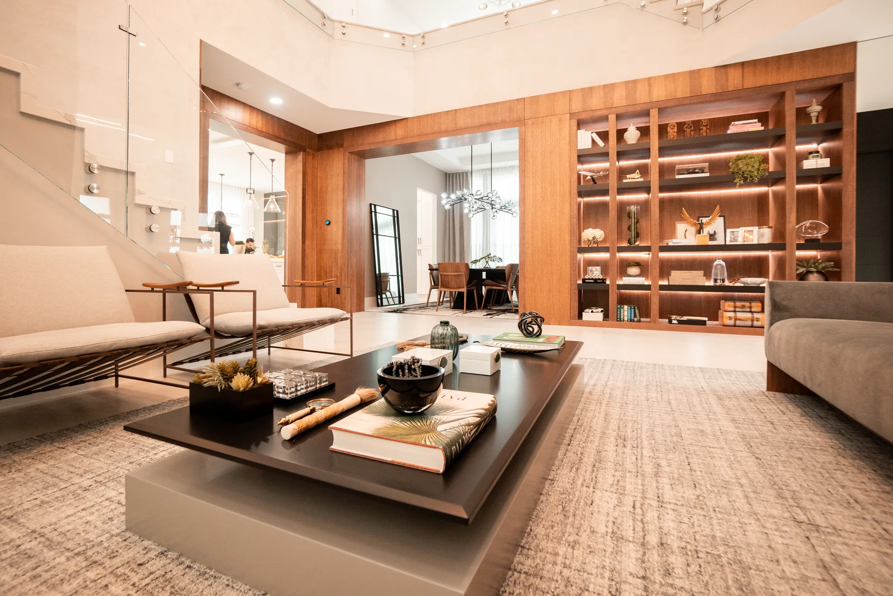 Living room with a floor-to-ceiling bookshelf wall and a sculptural staircase