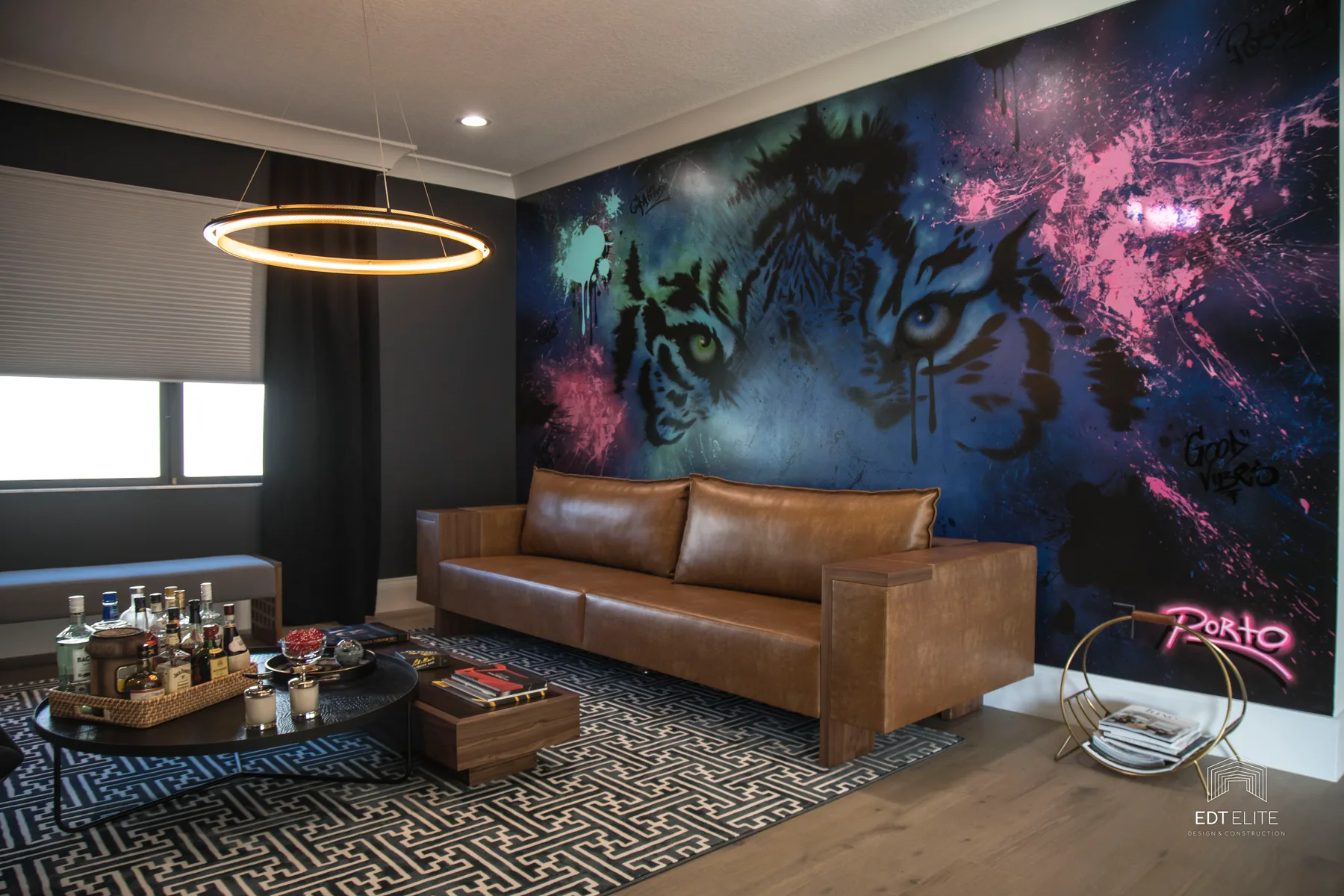 Lounge with a cosmic feature wall, caramel leather sofa and a graphic area rug