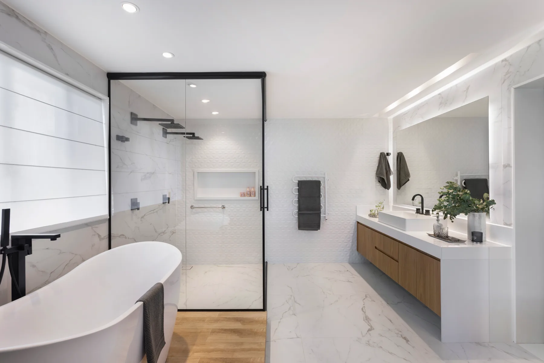 Bathroom with a freestanding tub, oak vanity and black-framed glass shower