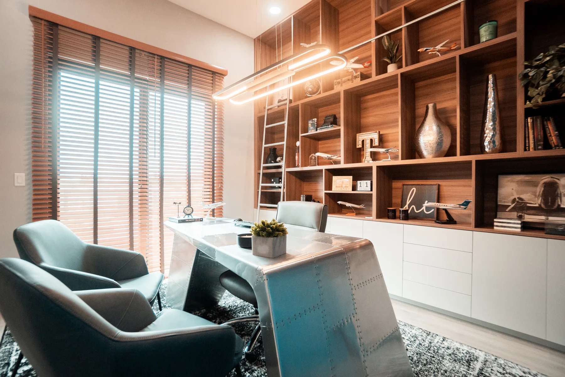 Home office with walnut shelving, a rolling ladder and a curved writing desk