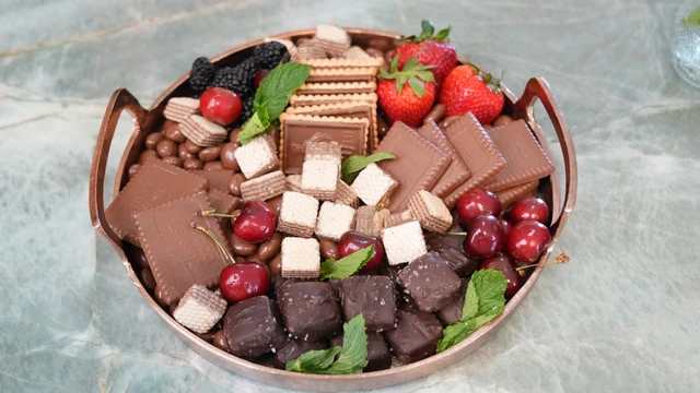 Tábua doce com chocolates, biscoitos, frutas e hortelã
